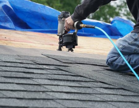handyman using nail gun to install shingle to repair roof